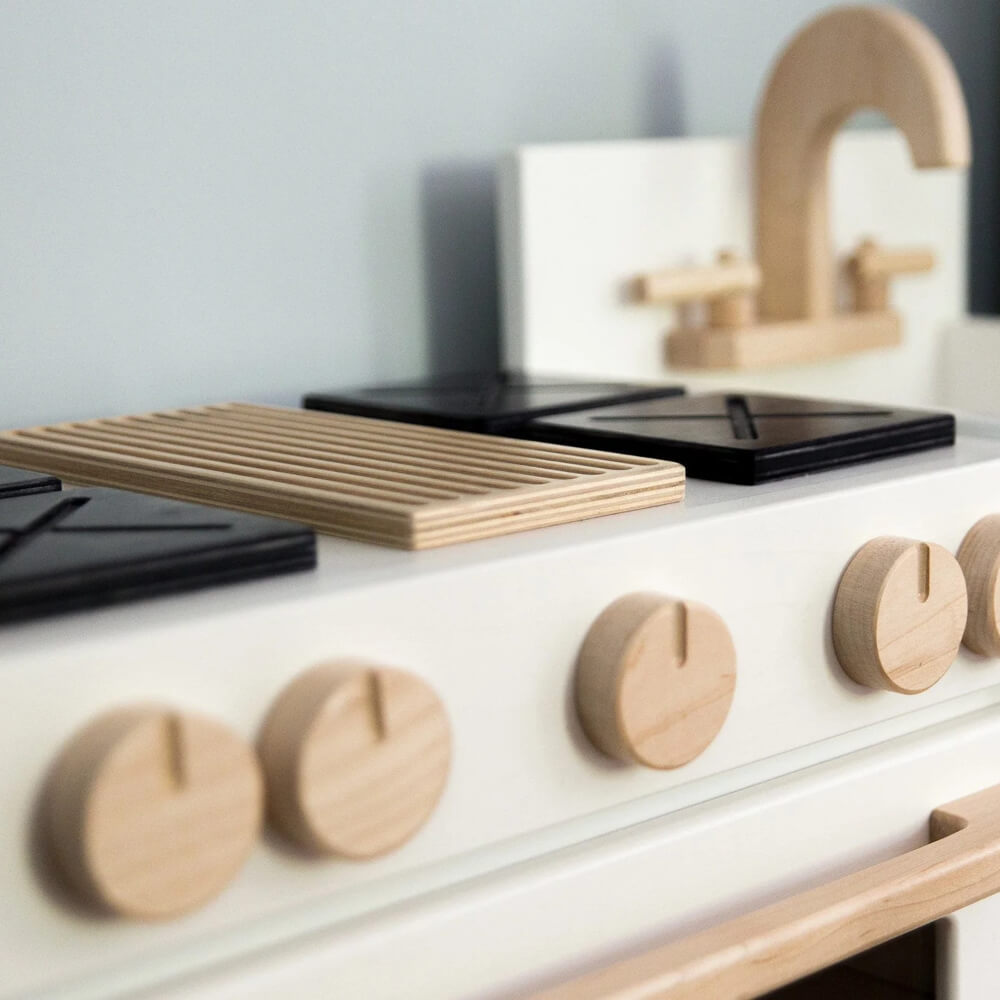 A close up of the milton & goose essential play kitchen oven knobs, grill, and burners