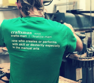 Person working on machine with shirt that says "Craftsman: one who creates or performs with skill or dexterity especially in the manual arts"