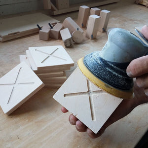 Milton and Goose team member sanding a play kitchen burner.