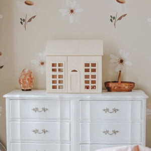 The Milton and Goose wooden dollhouse sits on top of a white dresser.
