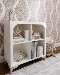 The wooden Archie Bookshelf by Milton & Goose is featured inside a nursery with baby toys and picture books stored inside. 