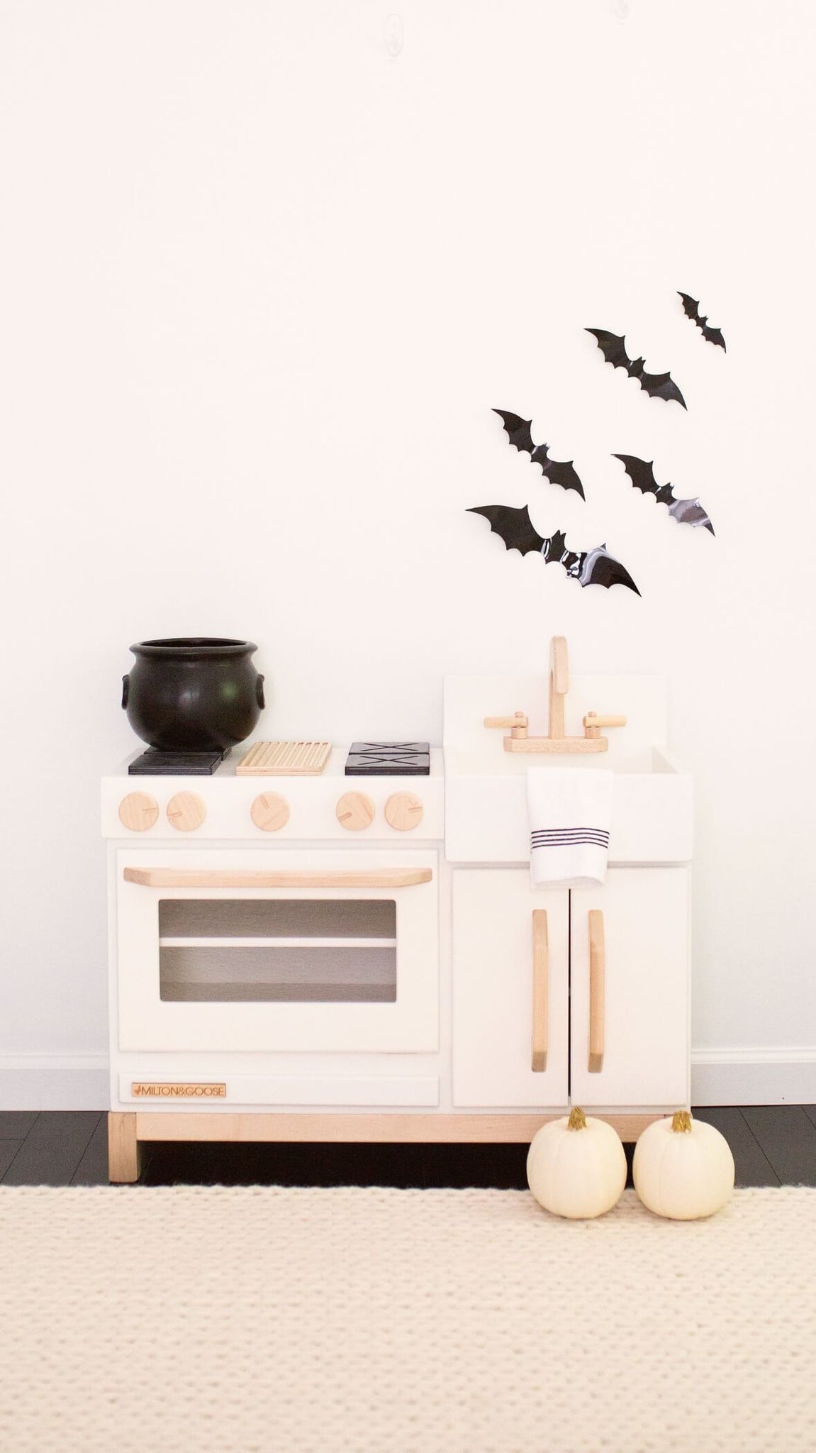 The essential wood play kitchen decorated for halloween with a witches cauldron and bats.