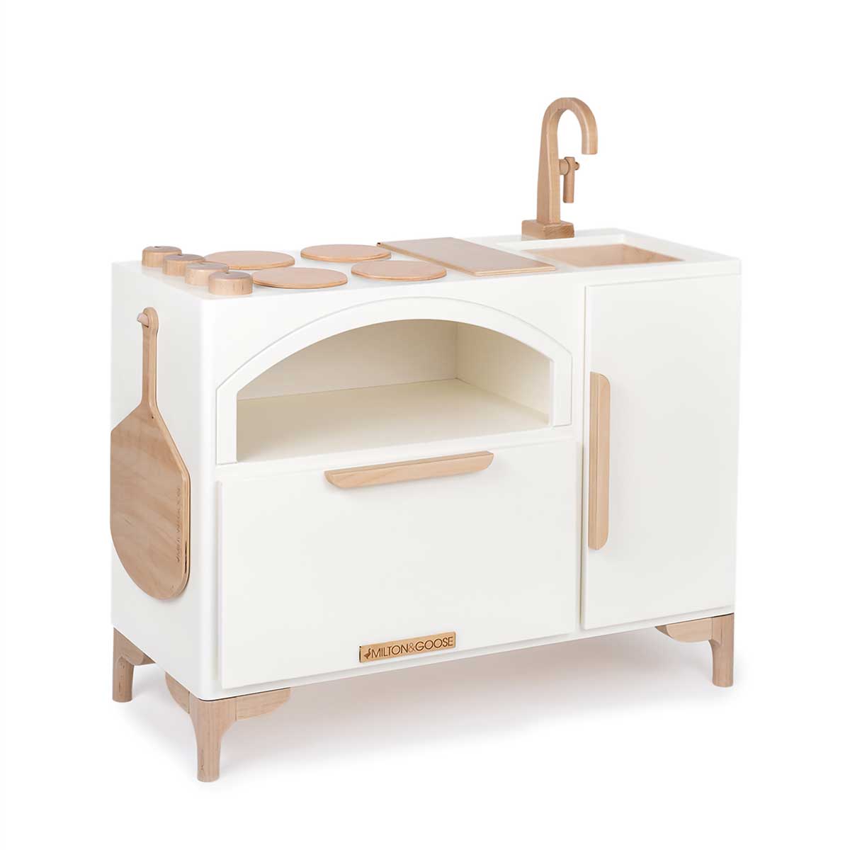 An angled view of the Milton & Goose Luca Wood Play Kitchen. The image shows off the pizza paddle which hangs from a hook on the side of the kitchen.