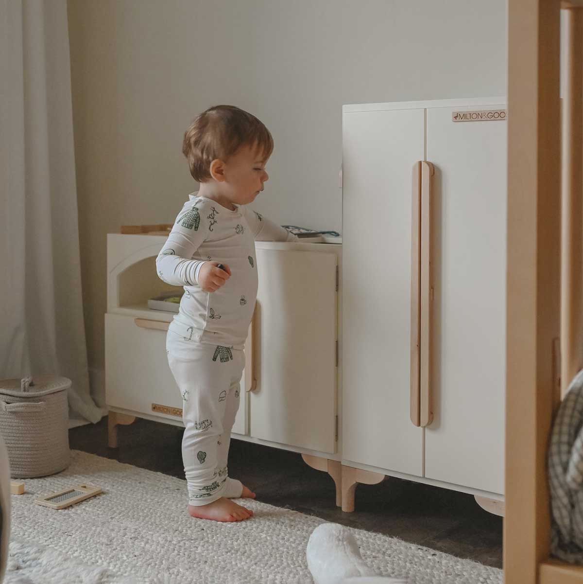 A toddler plays at his new Luca wood Play Kitchen and Refrigerator by Milton & Goose.