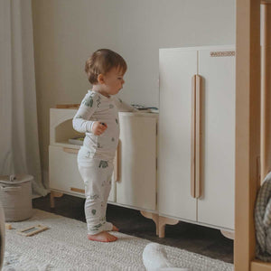 A toddler plays at his new Luca wood Play Kitchen and Refrigerator by Milton & Goose.