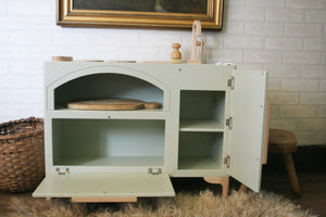 The milton and goose Luca Wood Play Kitchen in green is shown with the oven door and cabinet door open. Shows a large open cavity in the oven for pretend cooking and storage, along with two selves for storage inside the under sink cabinet. 