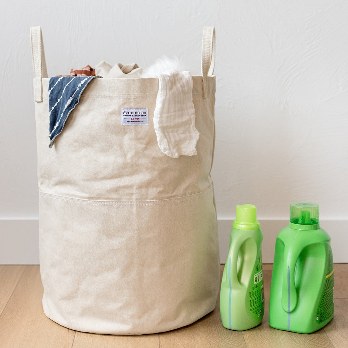 Tall canvas storage bin with laundry in it.