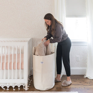 Woman organizing items in a large canvas storage bin in a nursery.