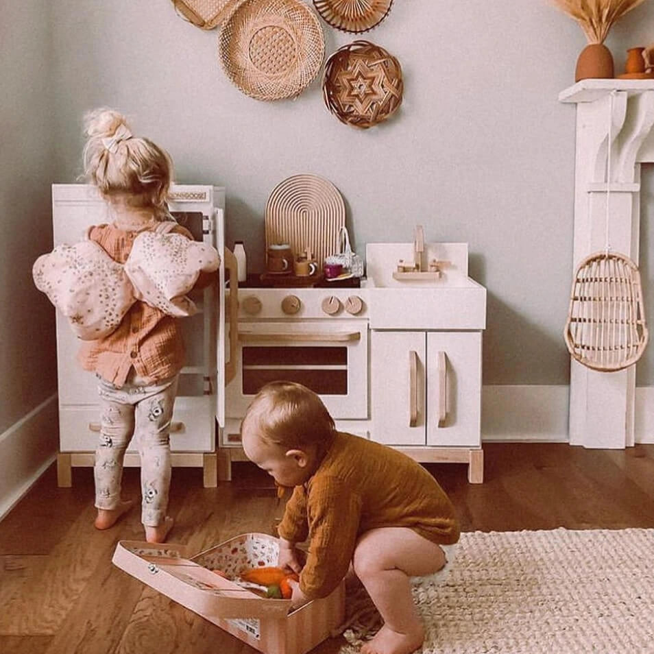 Milton & Goose Essential Play Kitchen and Refrigerator Set in White with children playing nearby.