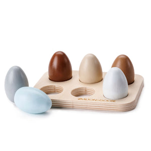 Milton & Goose's Half Dozen Egg Set painted in various shades of brown and blue to reflect the variety of natural chicken eggs. The six wooden eggs sit nestled in a wooden tray.