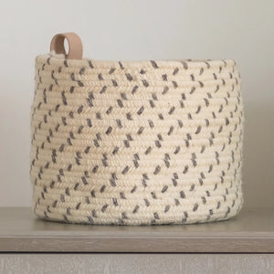 A closeup of the round braided basket with leather loop handle in gray.