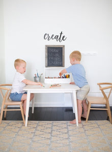 Children color on their Milton & Goose white table while seated in crescent chairs in natural color.