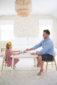 Dad and daughter play at Milton & Goose child sized table in white with coordinating crescent chairs in natural.