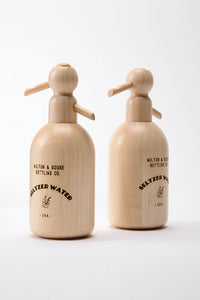 Two wooden seltzer bottle toys standing together.