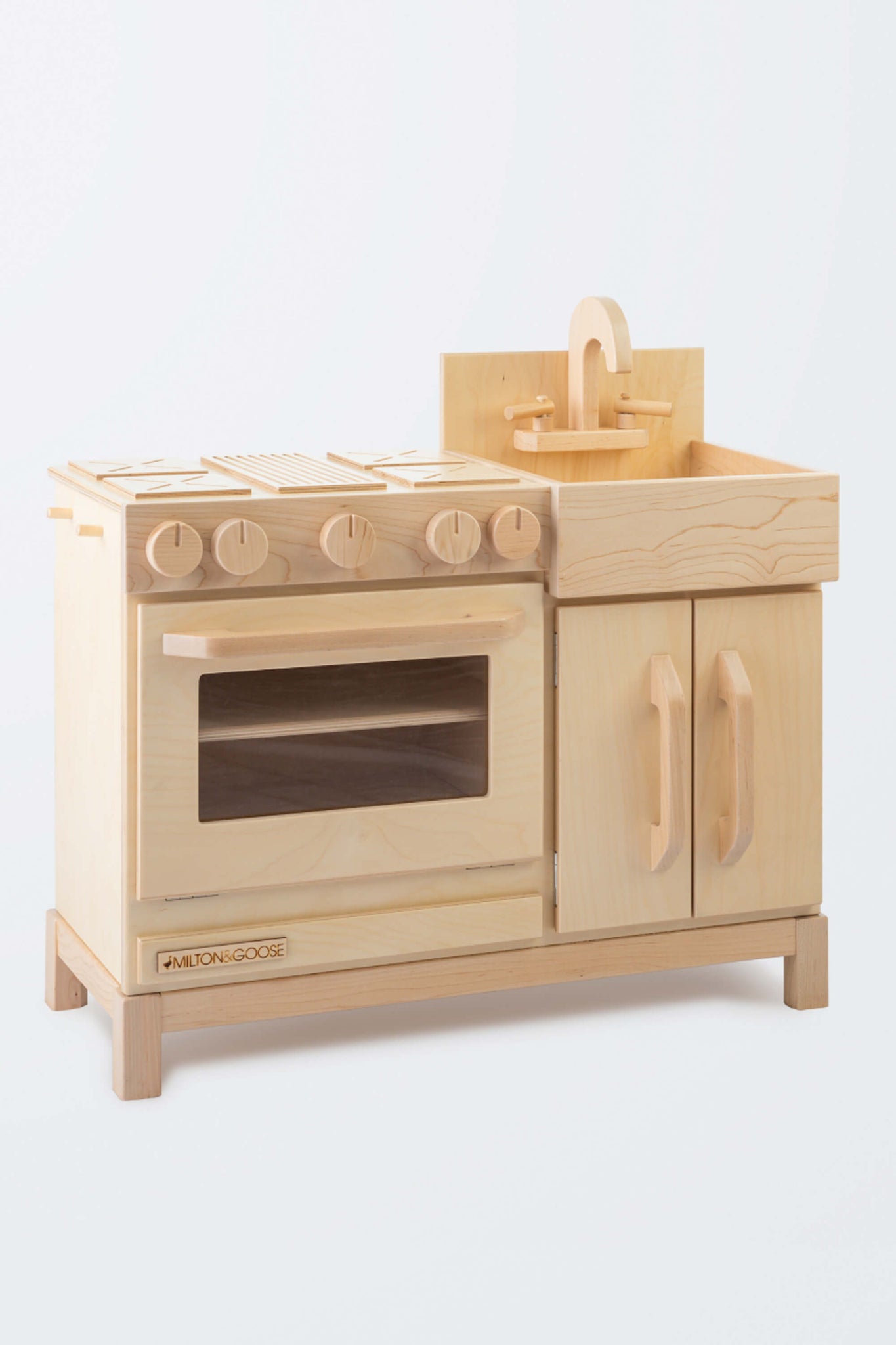 Milton & Goose Essential Play kitchen with a natural finish. The kitchen is turned so you can see the side. This wooden play kitchen is made with Baltic Birch Plywood and North American Maple wood.