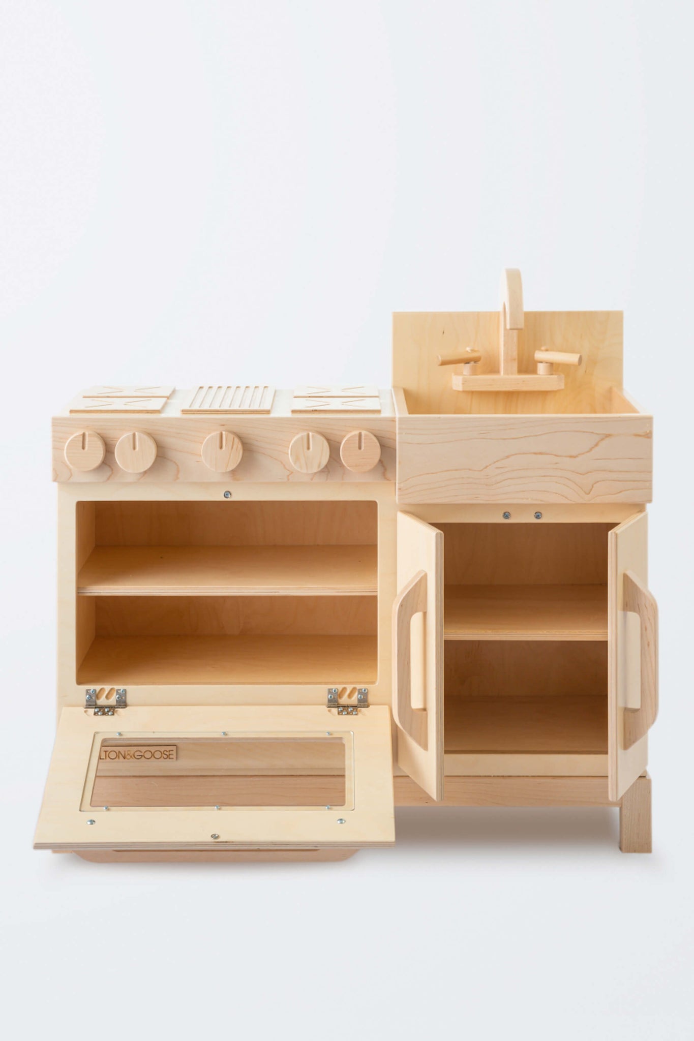 Milton & Goose Essential Play kitchen with a natural finish. The oven door and cabinet doors are open so you can peak inside. This wooden play kitchen is made with Baltic Birch Plywood and North American Maple wood.
